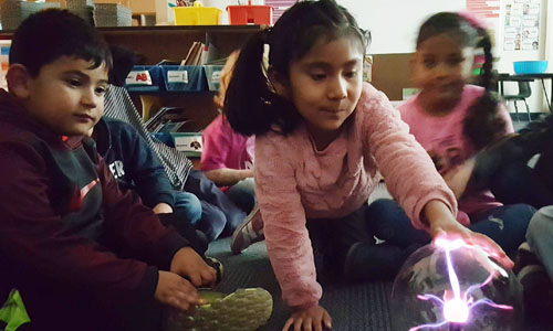 students touching a plasma globe 